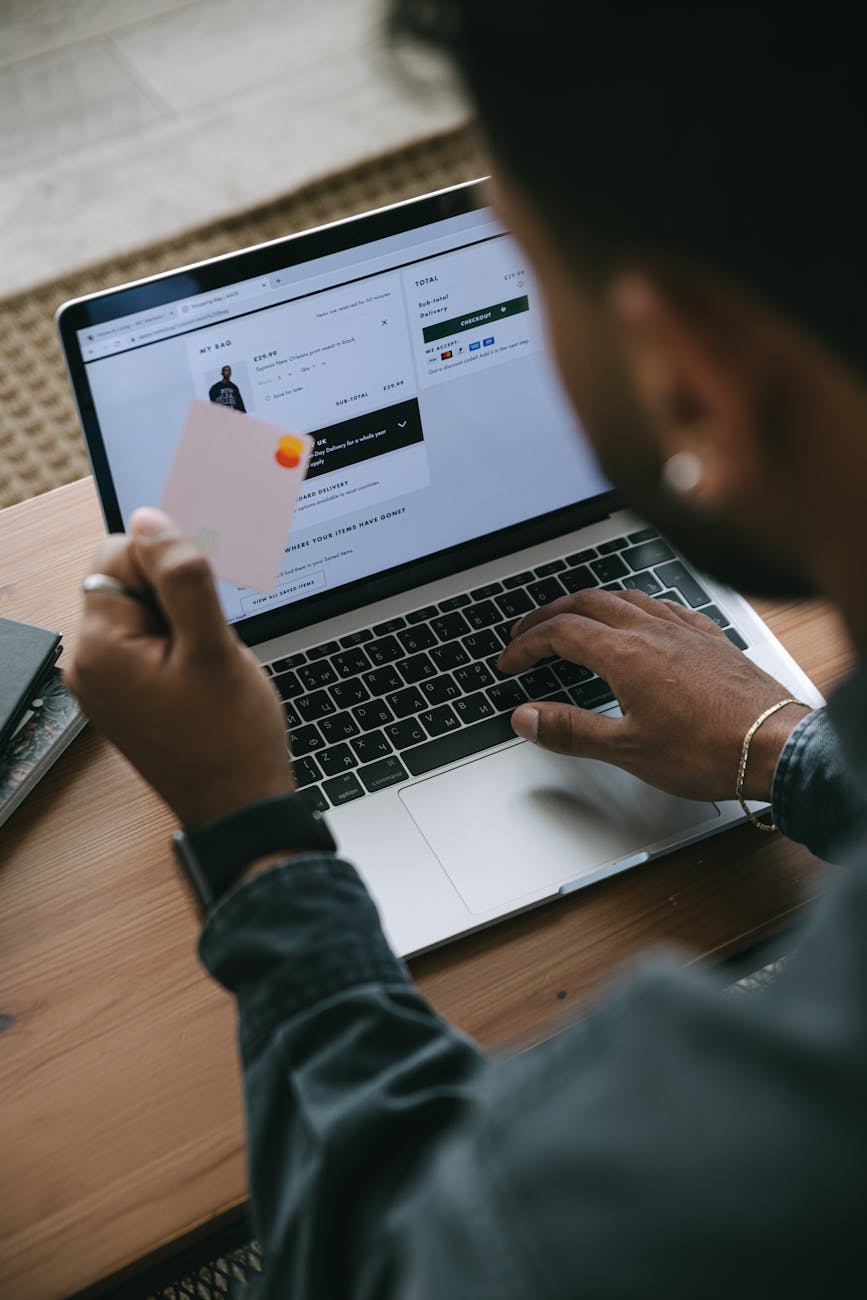 a man holding a card while using his laptop